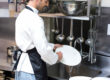 Handsome employee doing dishes in commercial kitchen
