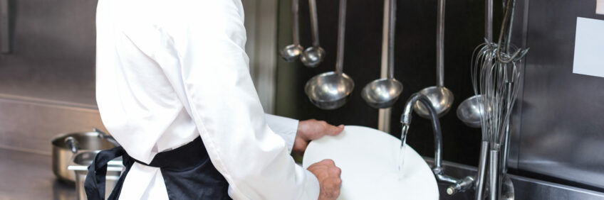 Handsome employee doing dishes Handsome employee doing dishes in commercial kitchen